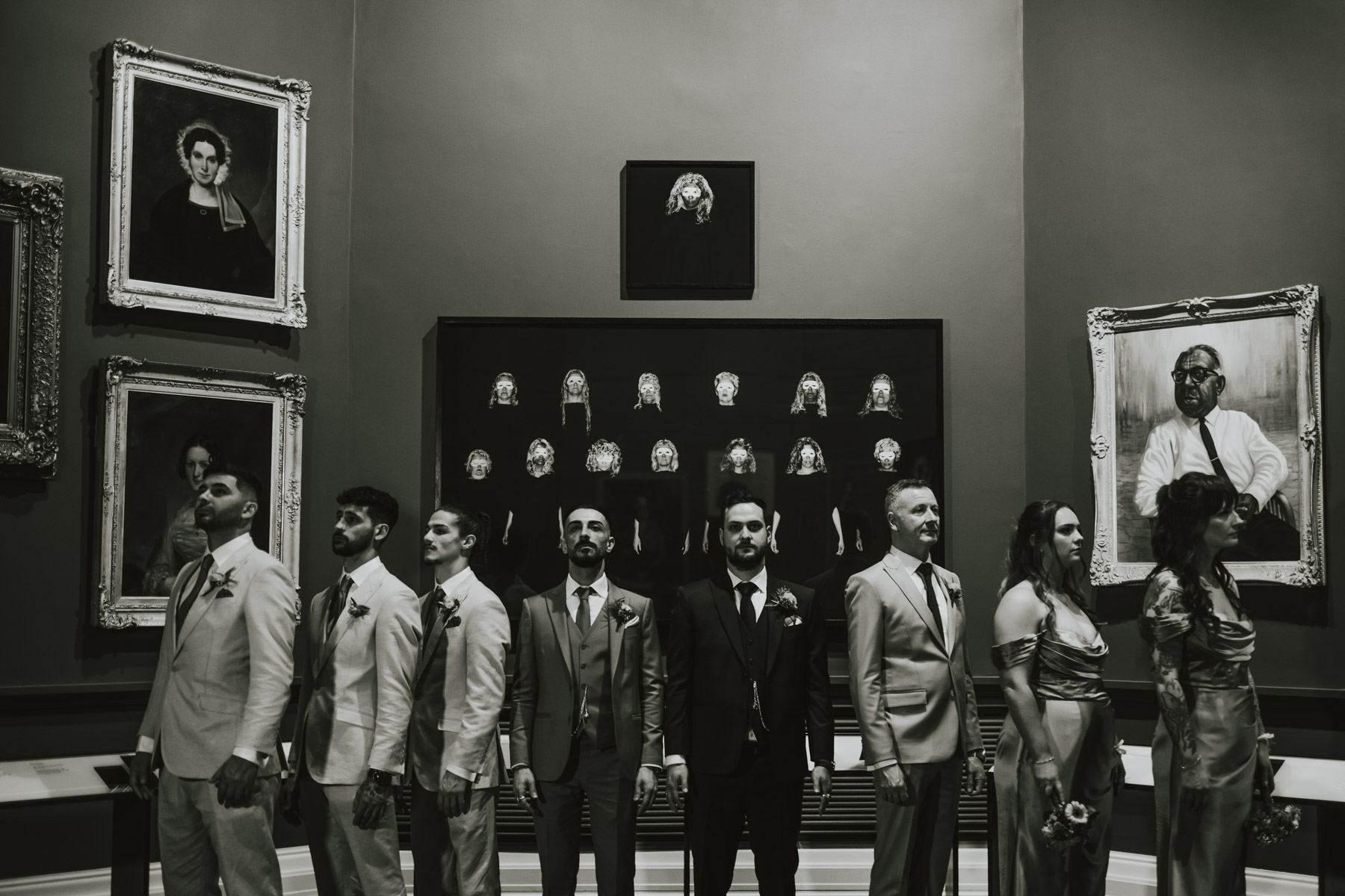 Wedding party posed in a dark portrait gallery