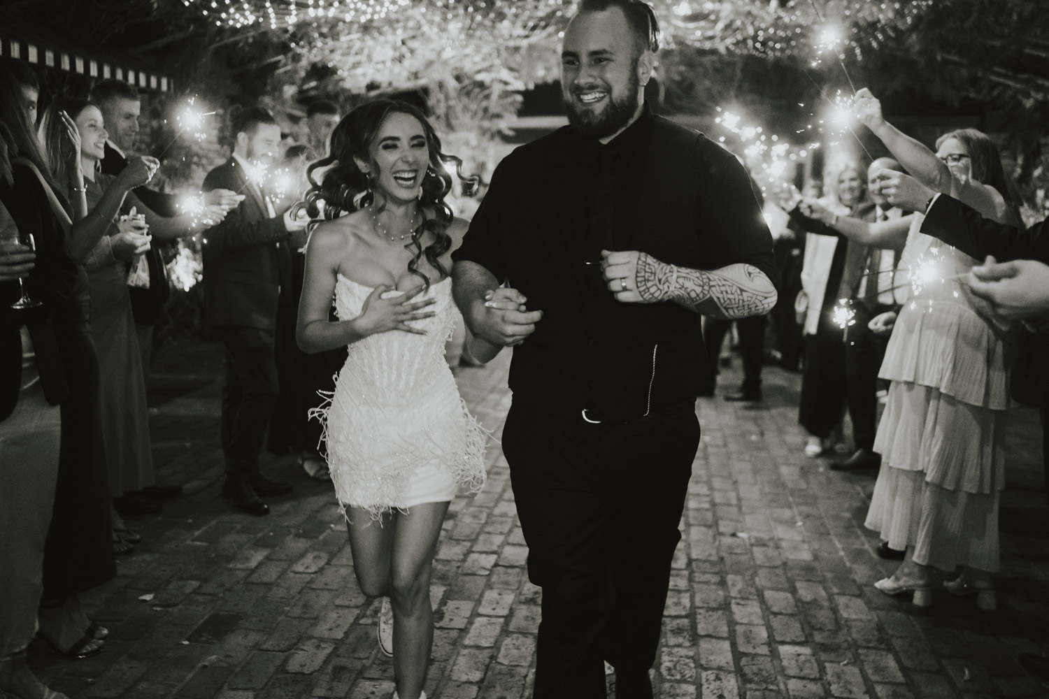 Newlyweds running through guests holding sparklers
