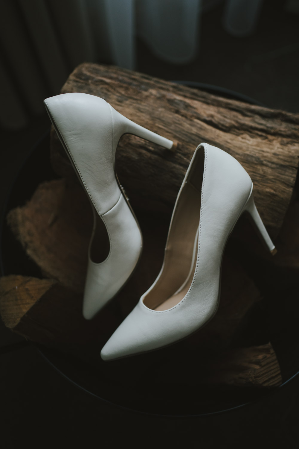 The bride's white shoes arranged on a rough wood log