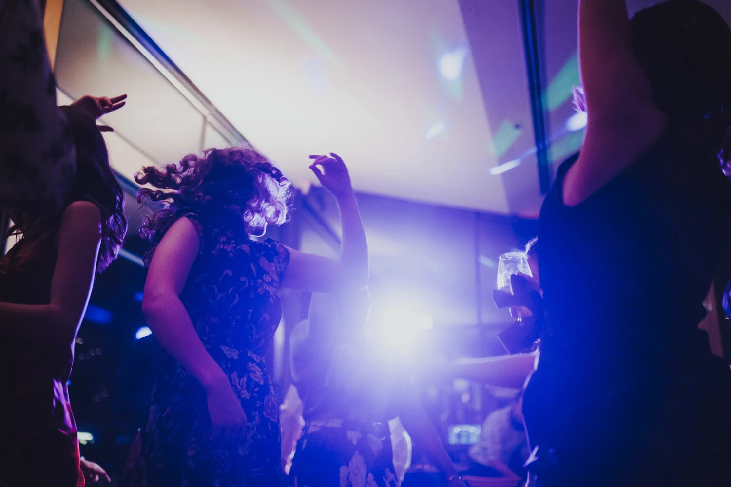 Guests dancing through violet and electric blue reception light