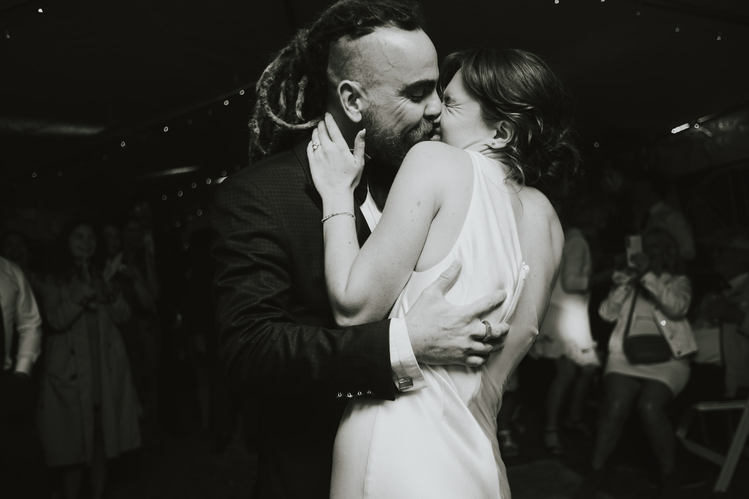 Newlyweds kissing in a dark reception crowd