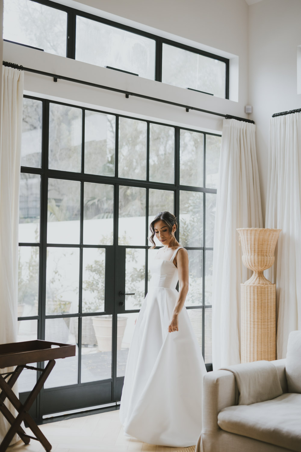 Bride standing against a grid of black-framed windows