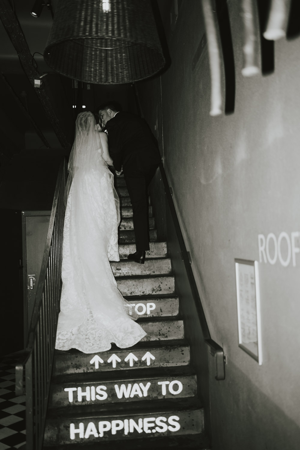 Newlyweds kissing on a staircase painted with the words This way to happiness