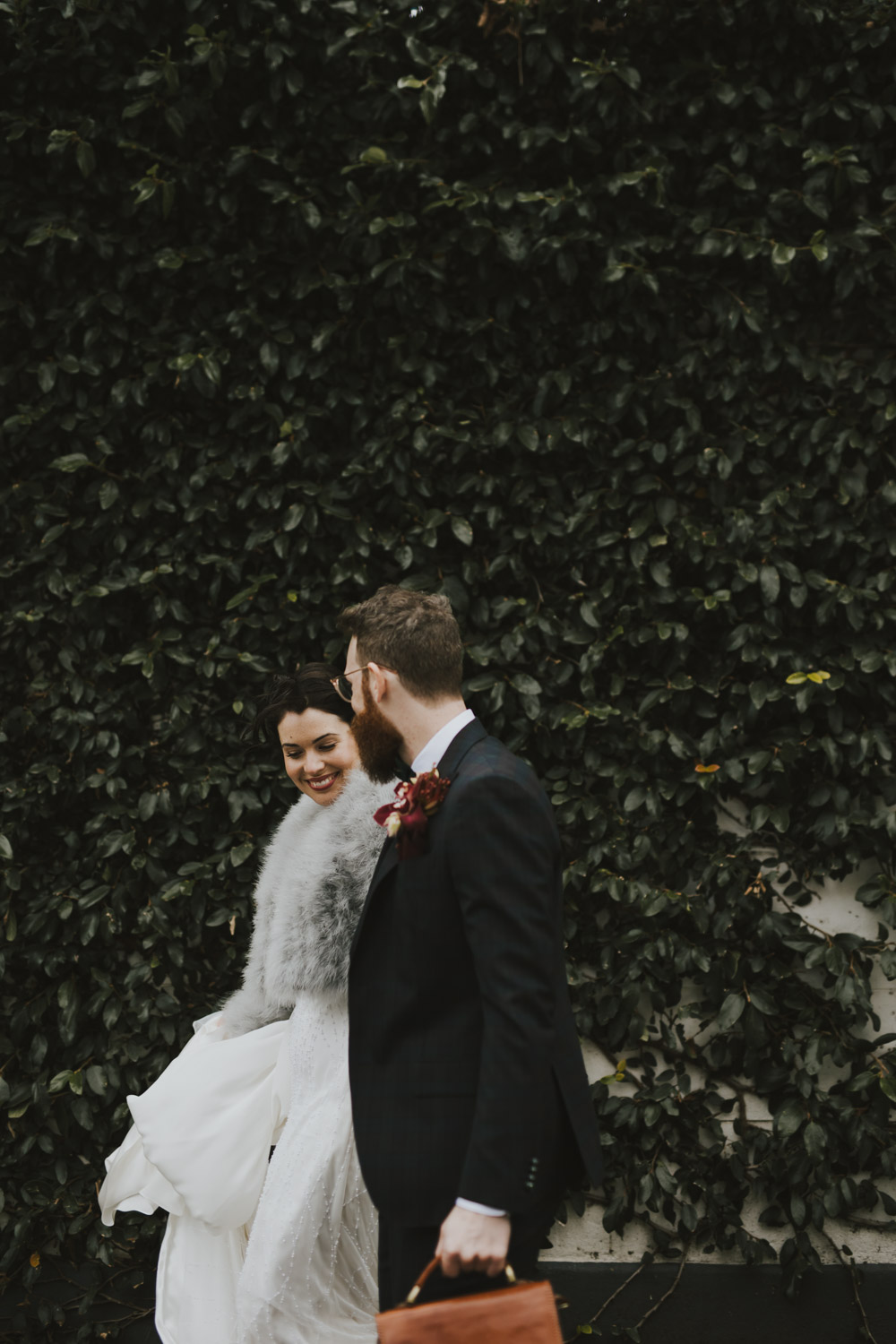 A bride smiling while walking beside her partner