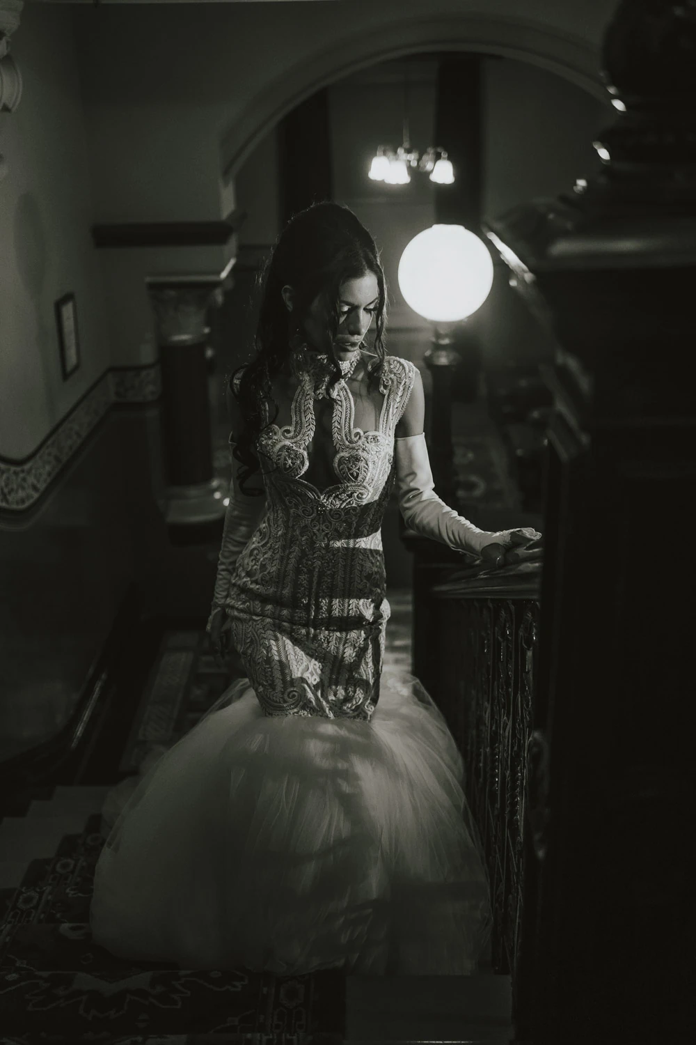 Black-and-white bridal portrait beside a glowing globe lamp on a staircase