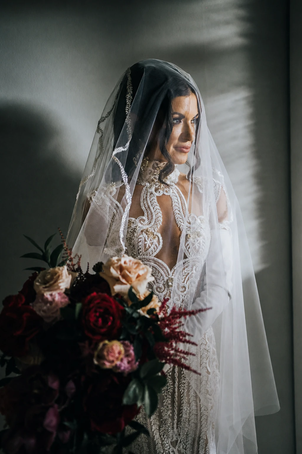 Fashion portrait of a bride beneath an embroidered veil